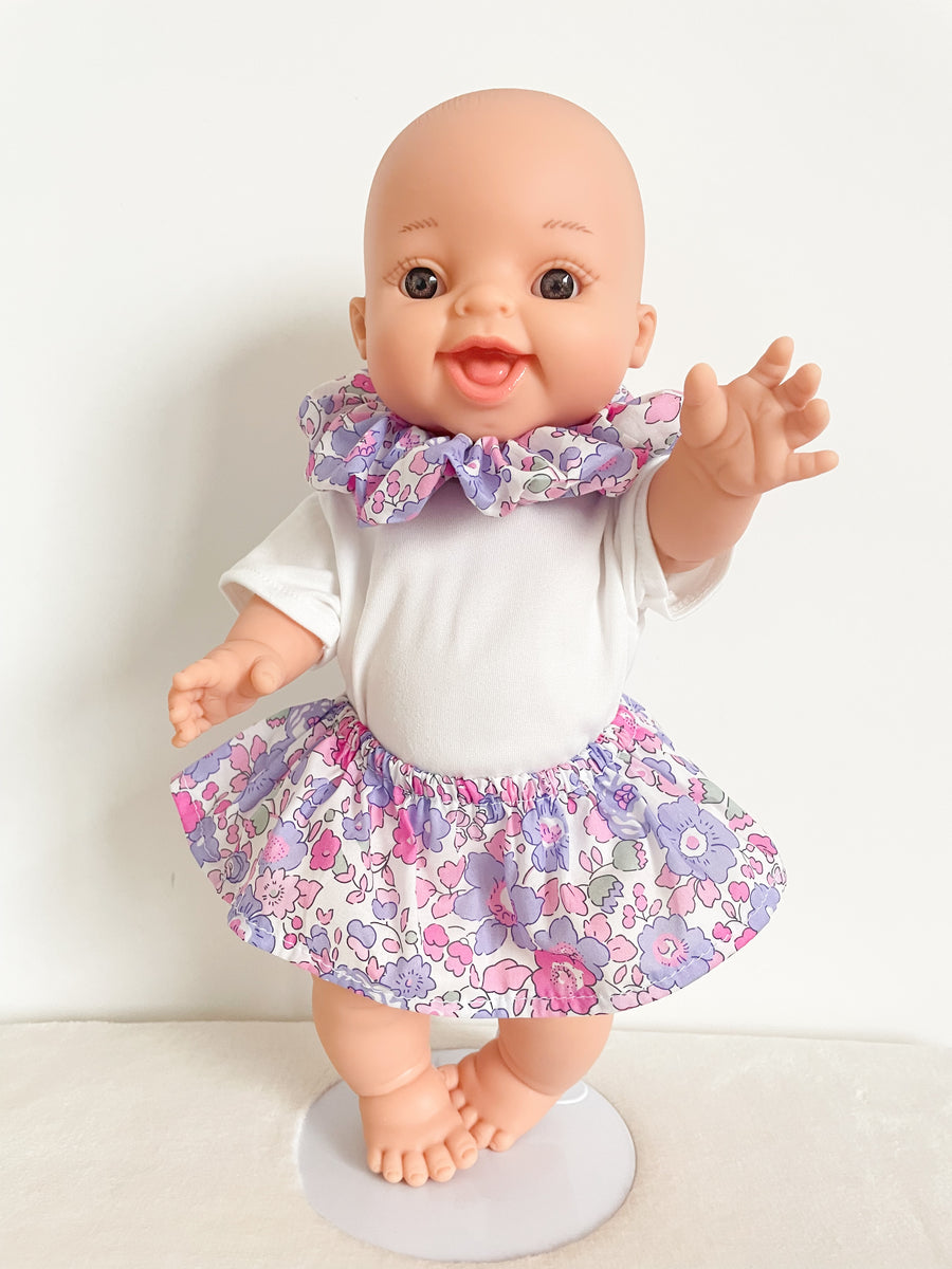 Poupon Gordi fille Paola Reina habillé par Les Juliettes Paris. L'ensemble comprend un poupon, une jupe, un tee shirt blanc et un col veritable chouchou en liberty lilas et rose